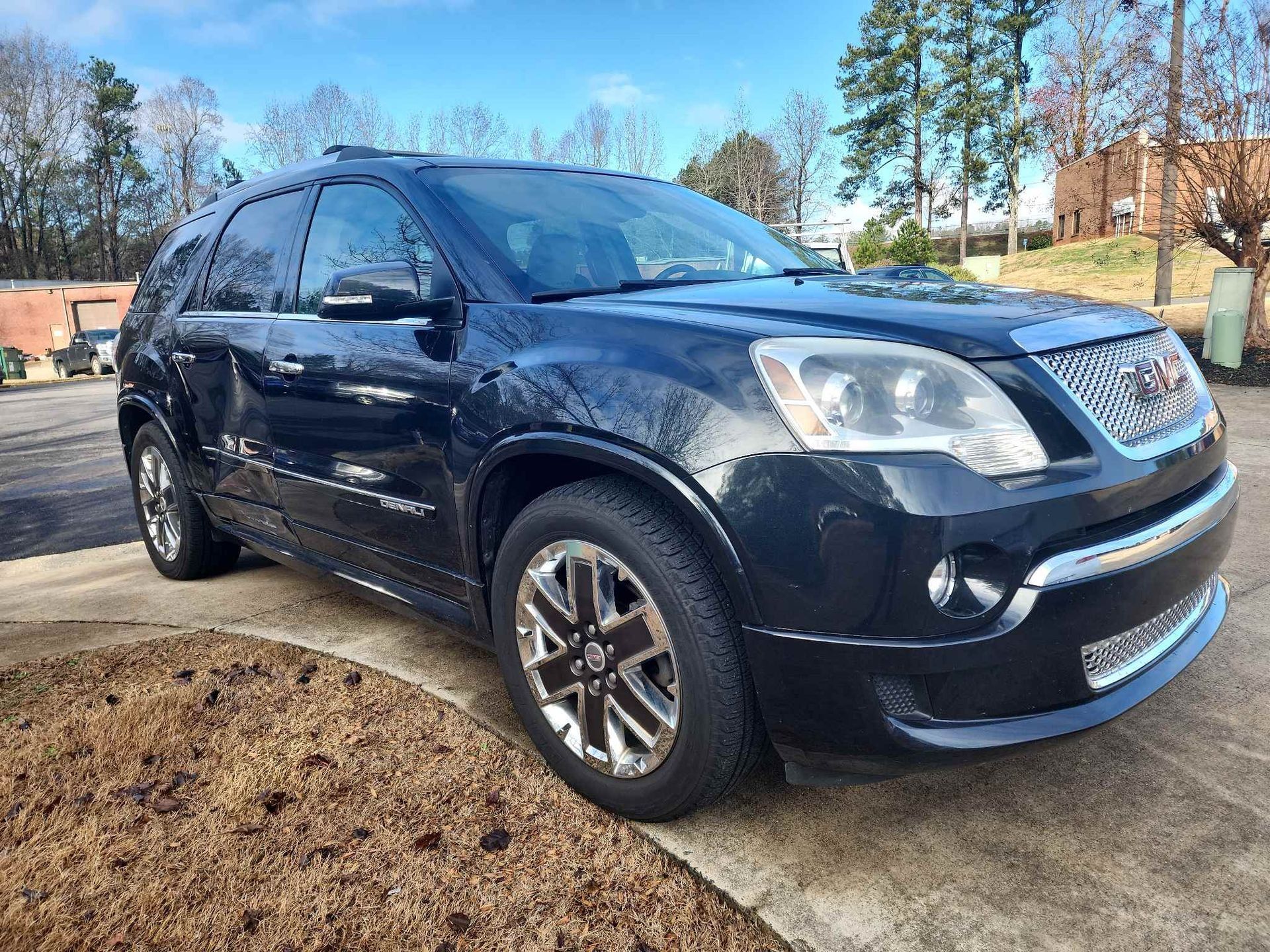 Dark blue SUV parked on a driveway with trees and blue sky in the background