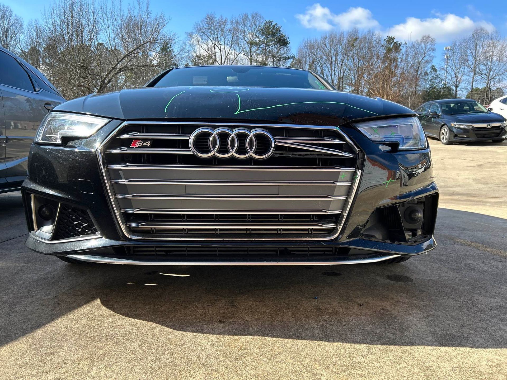 Black Audi sports sedan parked outdoors on a sunny lot, front view.
