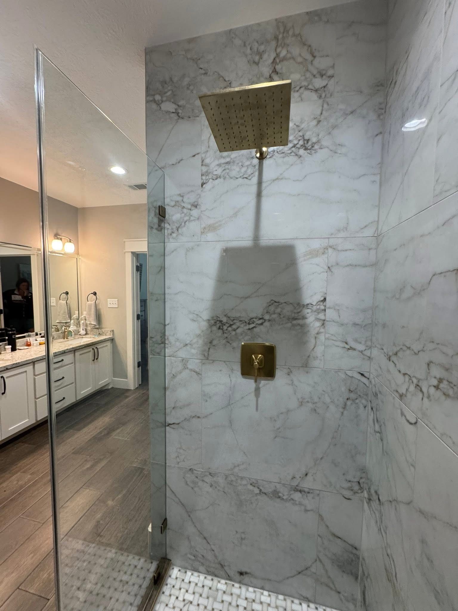 A bathroom with a walk in shower and a marble wall.