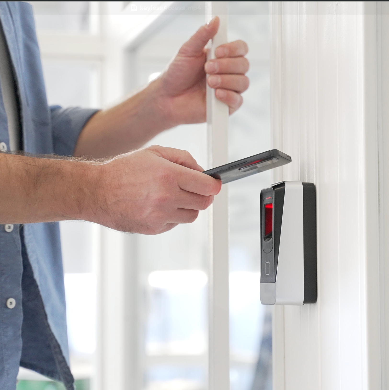 A man is using his phone to unlock a door with keyless access for businesses in Iowa.