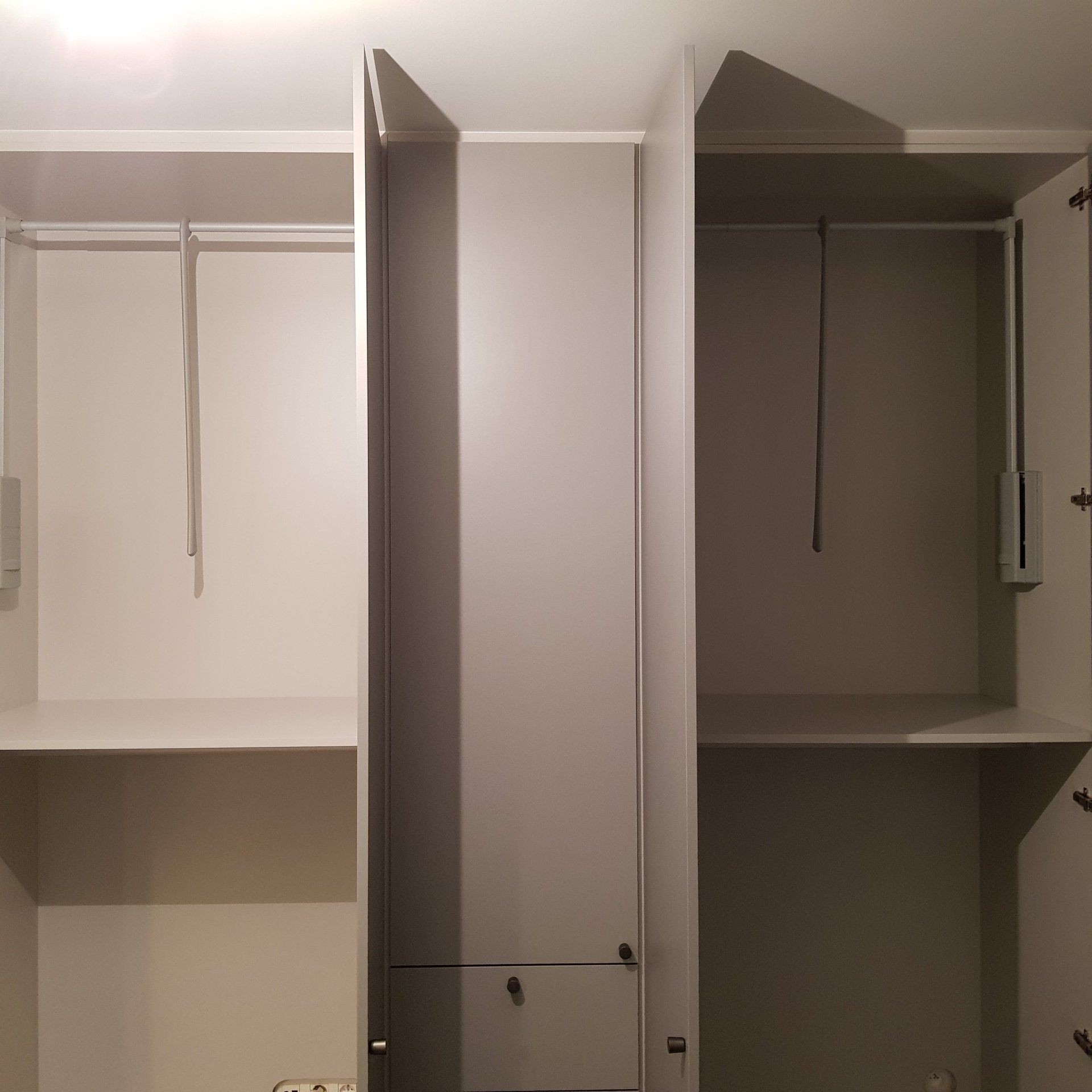 Lege witte kast met drie gedeeltes, elk met een hangroede en een plank.