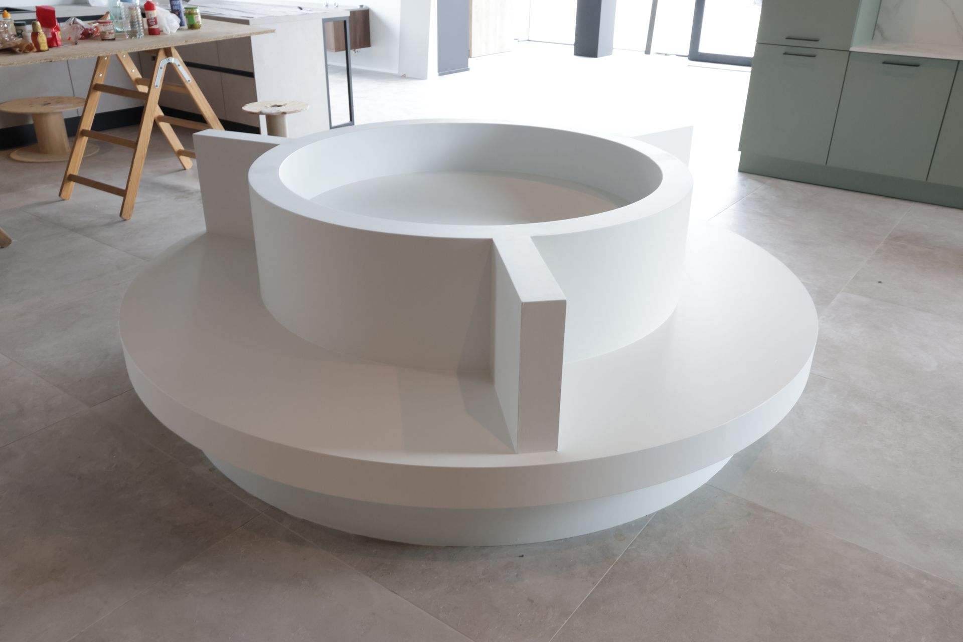 Een groot, wit, rond beeld met geometrische vormen in een binnenomgeving. Het werk heeft een verhoogde centrale ring.