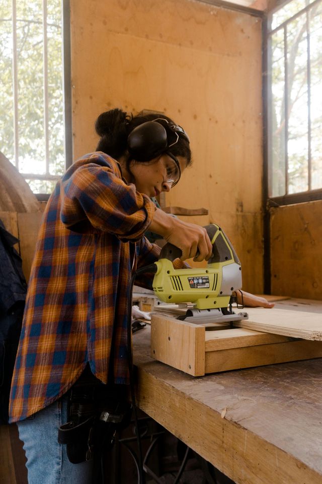 Een vrouw gebruikt een freesmachine om een stuk hout te zagen.