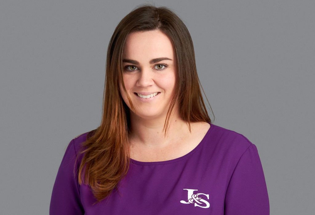 A woman is wearing a purple shirt and smiling.