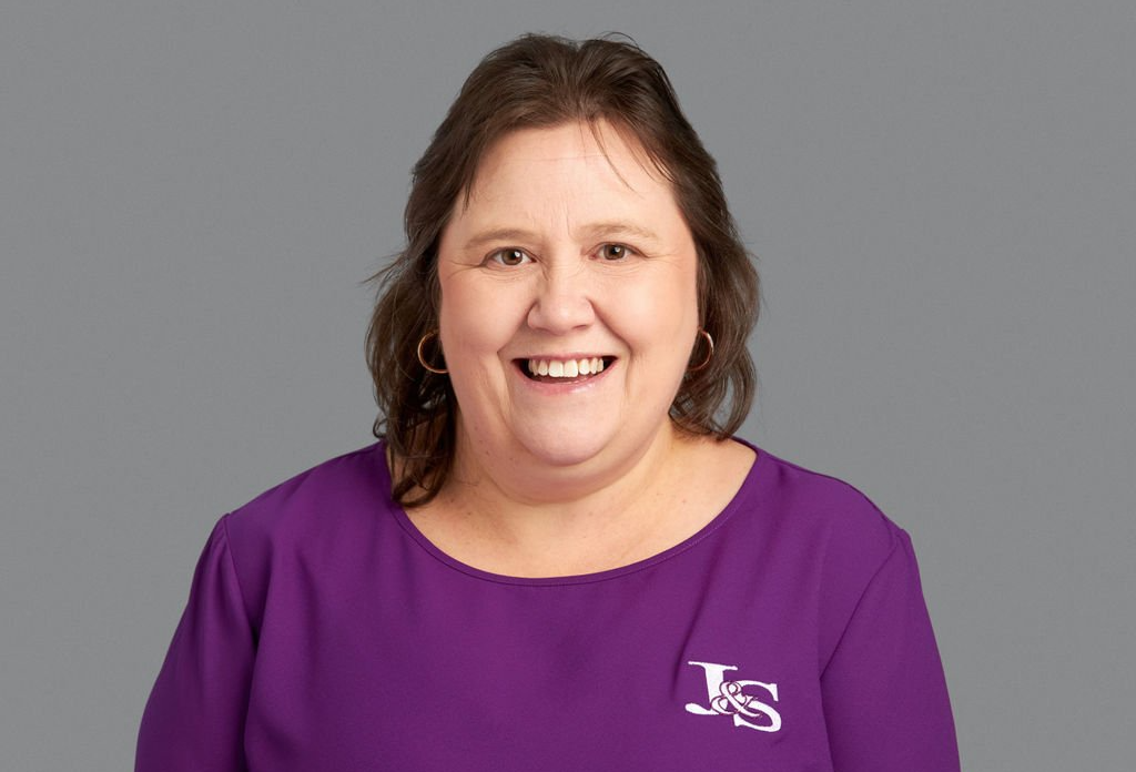 A woman in a purple shirt is smiling for the camera.