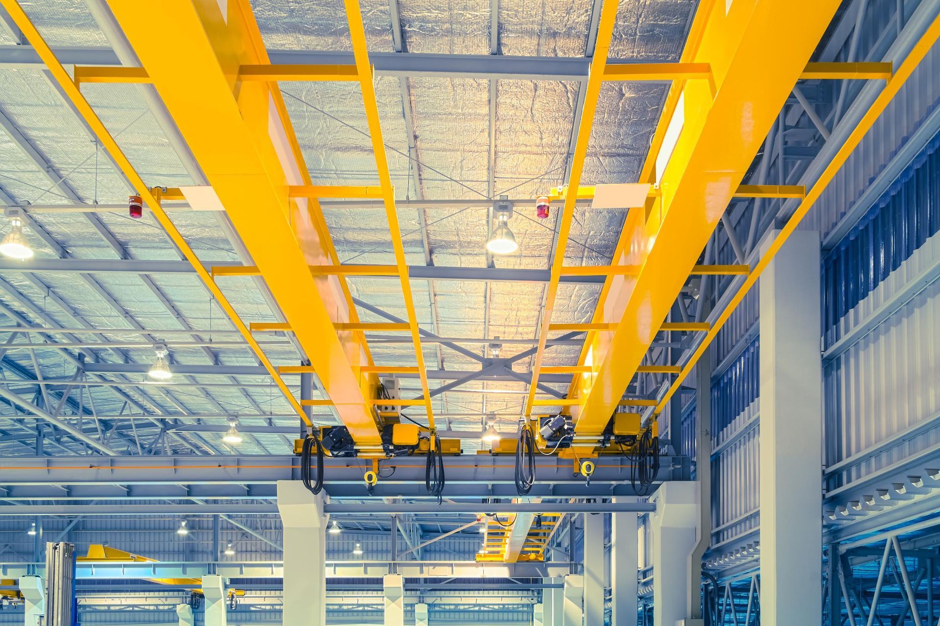 Yellow overhead crane system inside a factory. Metal beams and infrastructure.