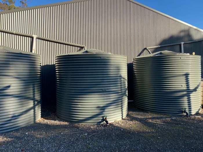 Two landscapers: one mowing grass on a tractor, the other using a weed whacker. Sunny day.