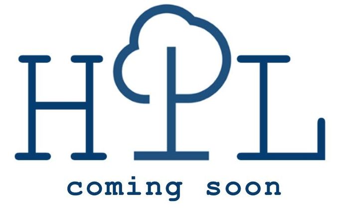 A person in green overalls prunes a bush with a yellow handled tool. Grass and landscaping in view.