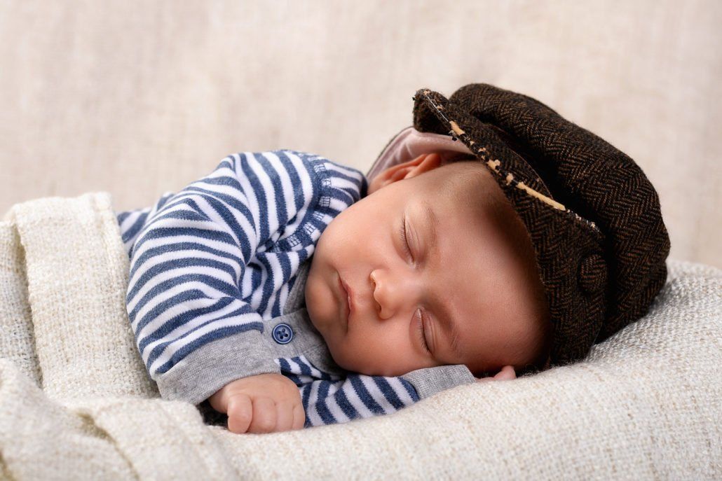 Ein Baby mit Hut schläft auf einer Decke