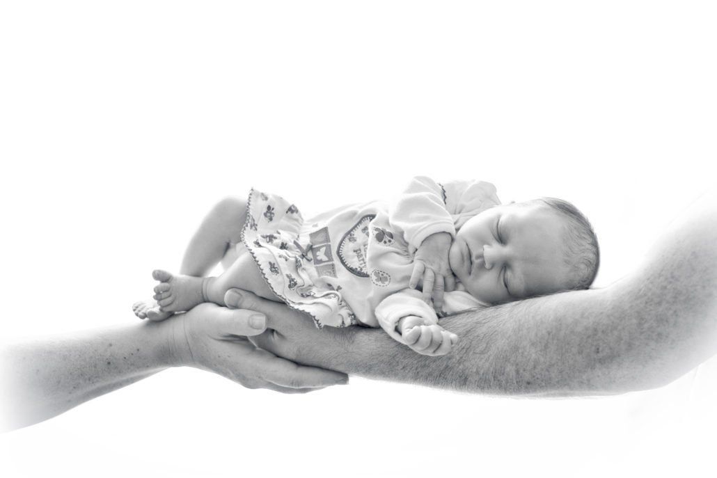 Ein Schwarzweißfoto einer Person, die ein Baby im Arm hält.