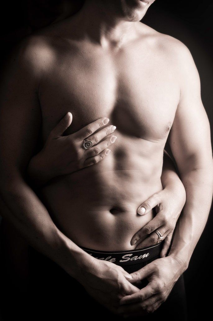 Ein Mann ohne Hemd wird von einer Frau umarmt