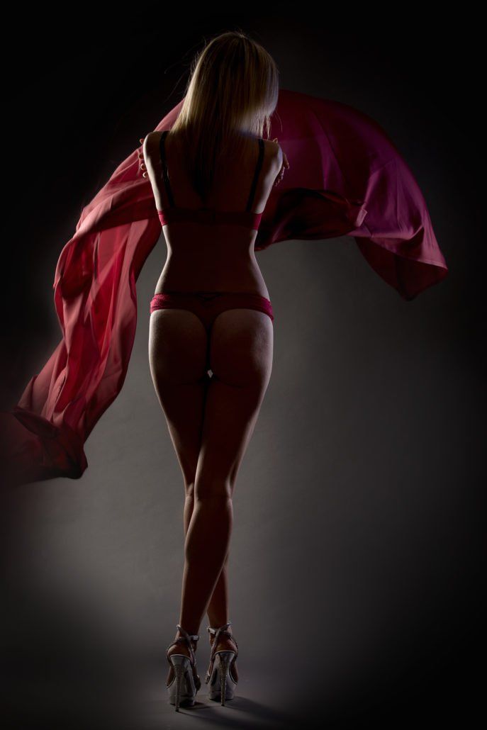 Eine Frau in Unterwäsche steht im Dunkeln und hält ein rotes Tuch.