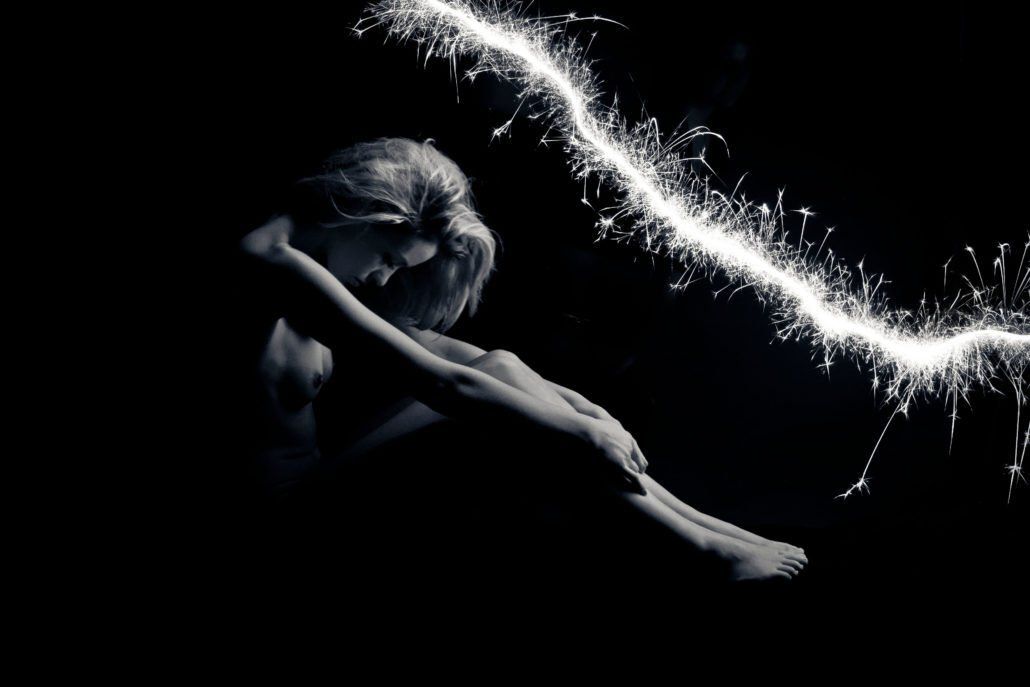 Ein Schwarzweißfoto einer Frau, die im Dunkeln sitzt