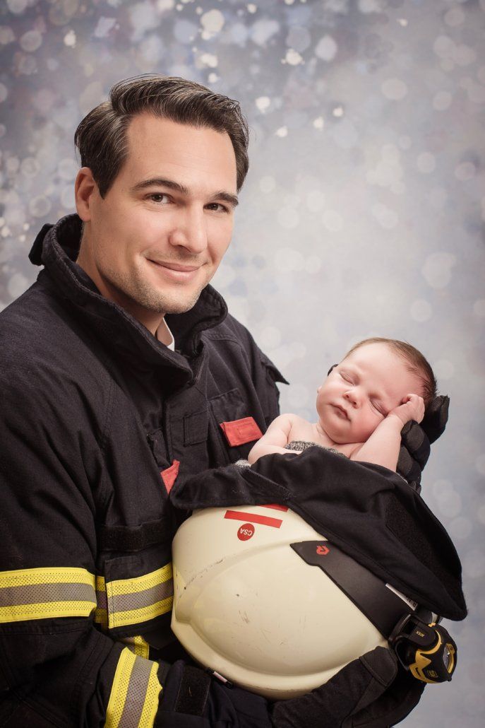 Ein Mann in einer Feuerwehruniform hält ein Baby in seinen Armen