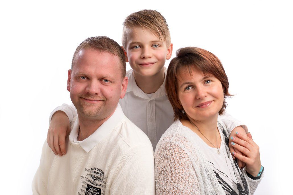 Eine Familie posiert gemeinsam für ein Foto vor einem weißen Hintergrund.