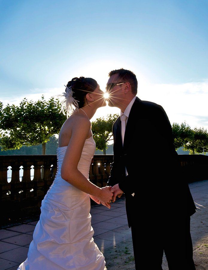 Eine Braut und ein Bräutigam küssen sich und halten dabei die Hände