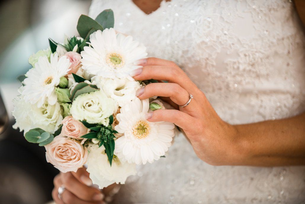 Die Braut trägt einen Ehering und hält einen Blumenstrauß in der Hand.