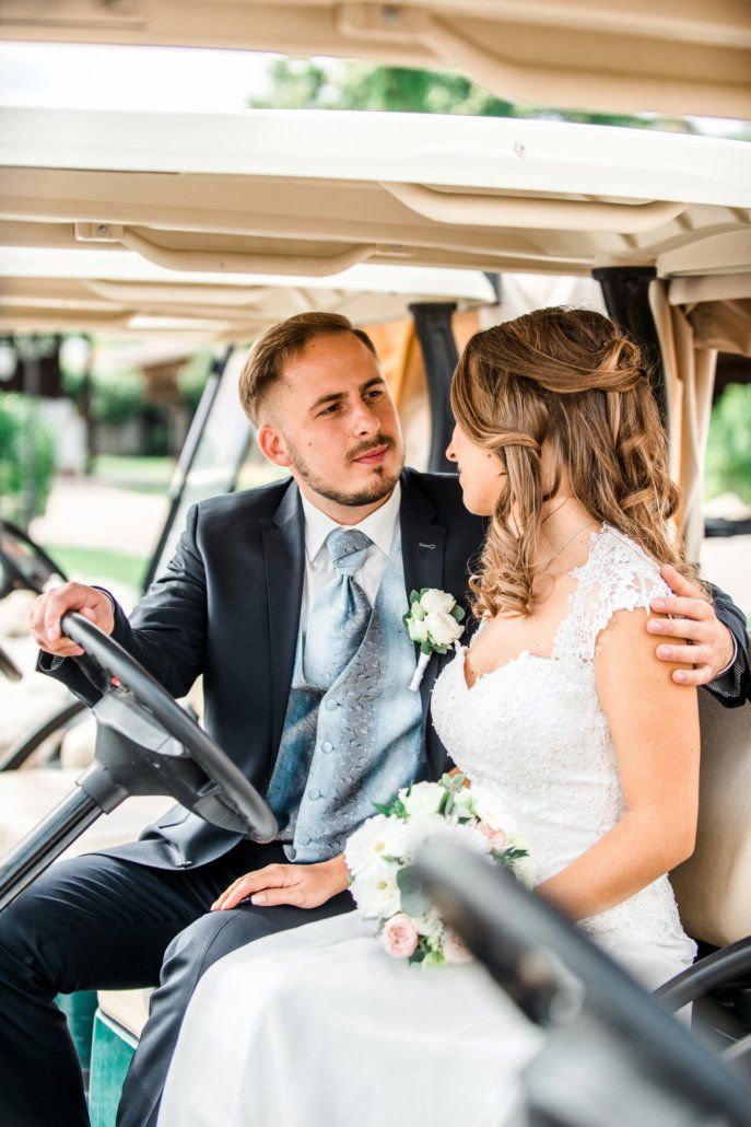 Eine Braut und ein Bräutigam sitzen in einem Golfwagen.