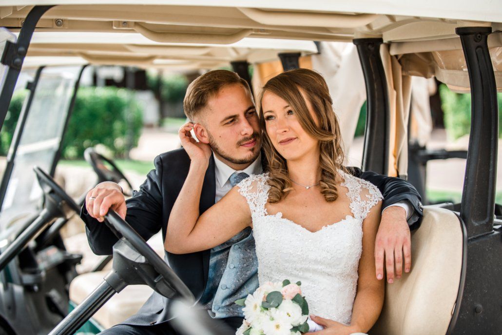 Eine Braut und ein Bräutigam sitzen auf dem Rücksitz eines Golfwagens.
