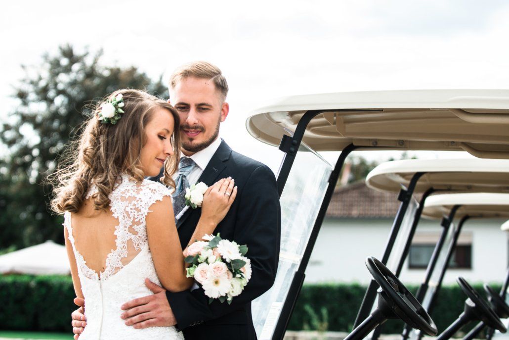 Eine Braut und ein Bräutigam posieren für ein Foto vor einem Golfwagen.