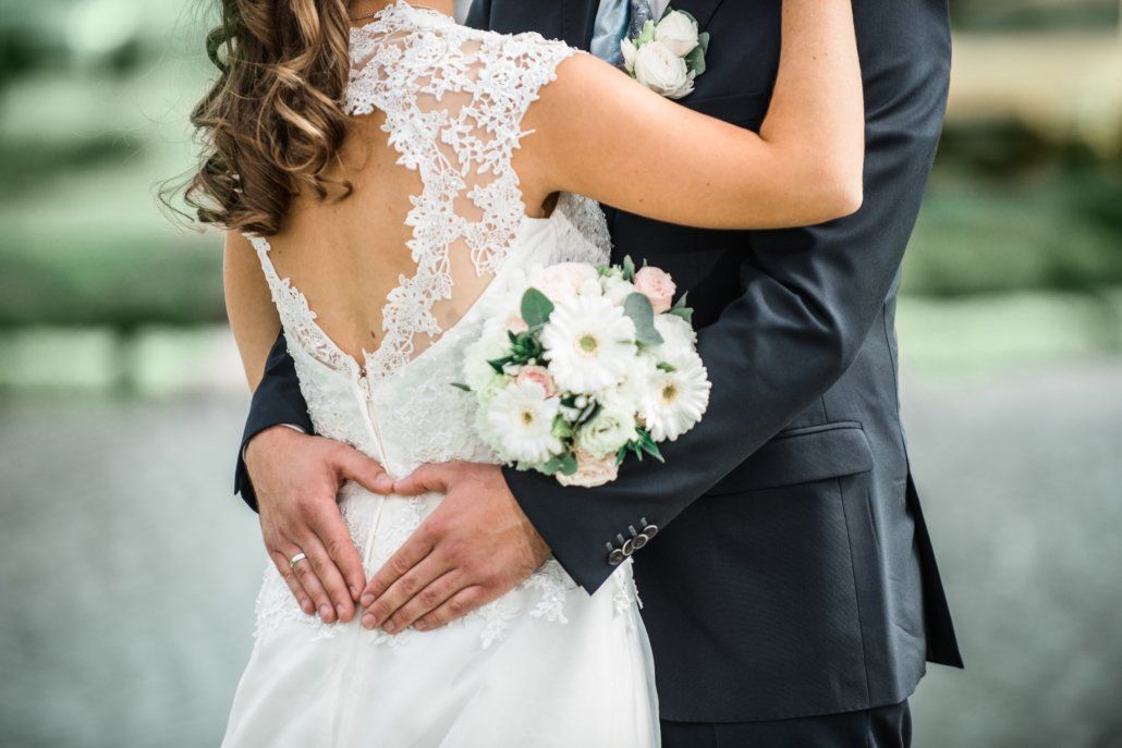 Eine Braut und ein Bräutigam formen mit ihren Händen ein Herz.