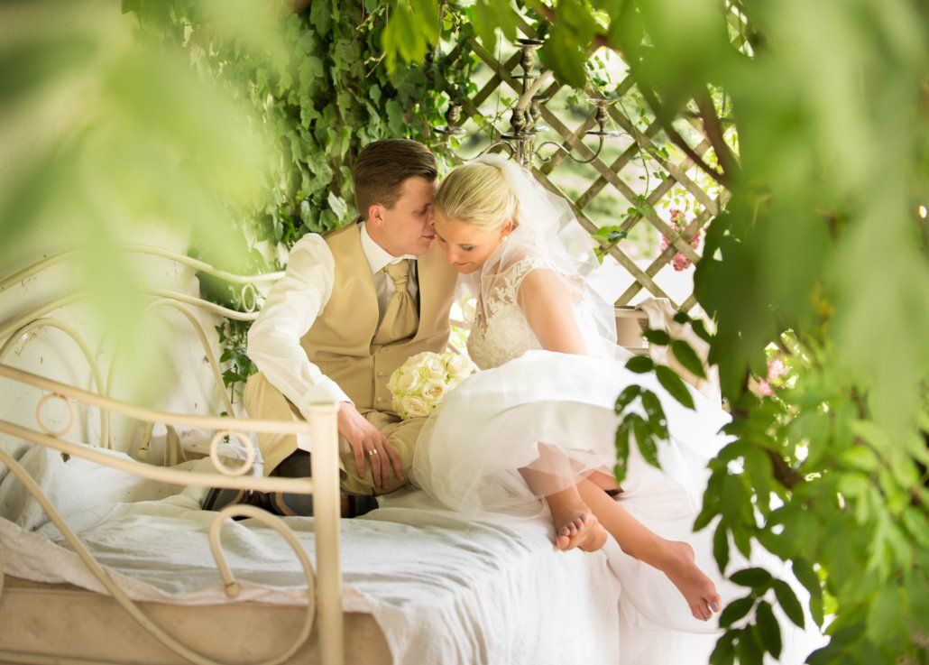 Eine Braut und ein Bräutigam sitzen auf einem Bett unter einem Baum.