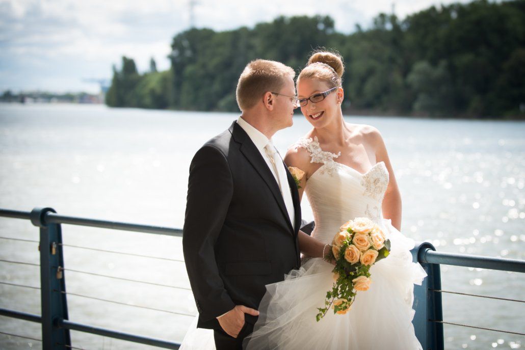 Eine Braut und ein Bräutigam posieren vor einem Gewässer für ein Foto.