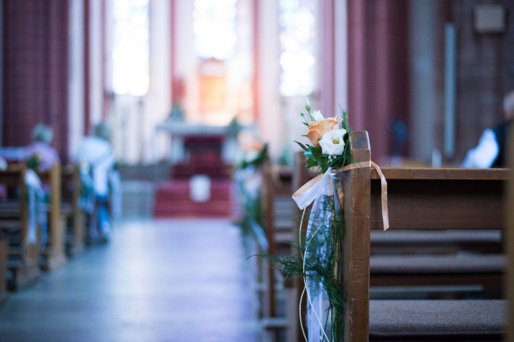 Eine Kirche wird für eine Hochzeitszeremonie mit Blumen und Bändern geschmückt.