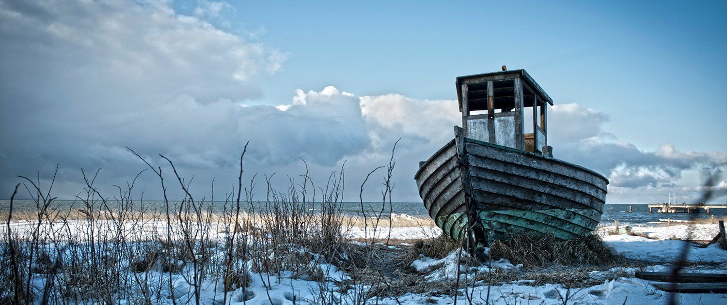 Ein altes Boot liegt am Ufer eines Sees.