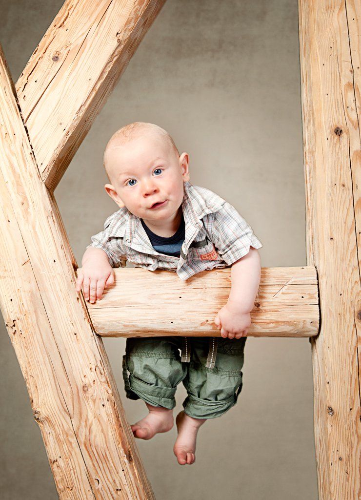 Ein Baby sitzt auf einem Holzbalken.