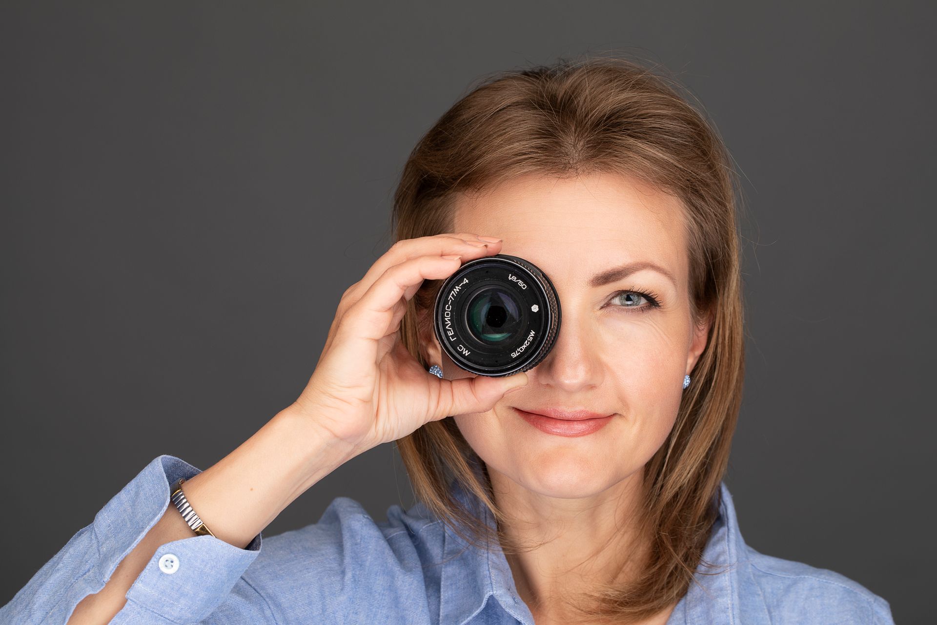 Eine Frau hält ein Kameraobjektiv vor ihr Auge.