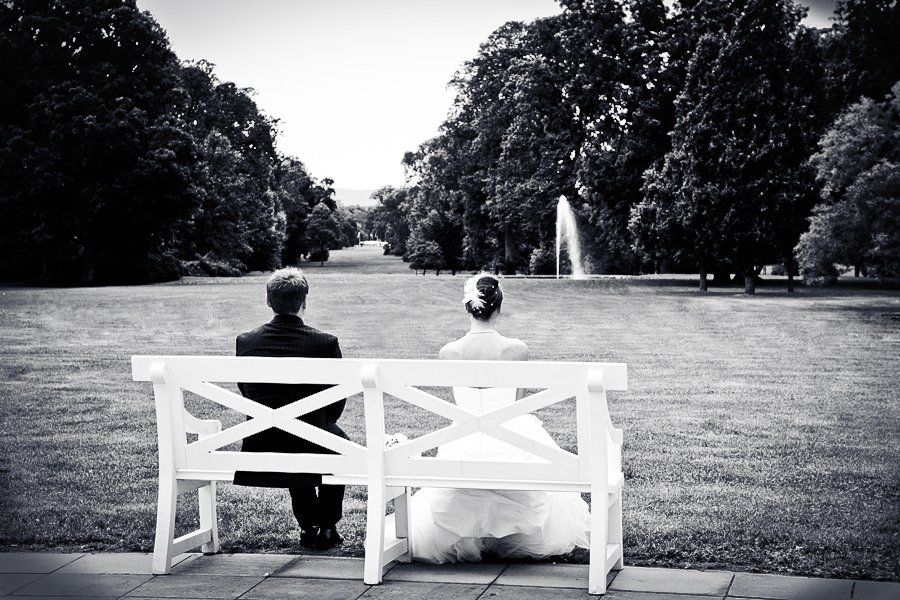 Ein Schwarzweißfoto von einer Braut und einem Bräutigam, die auf einer Bank sitzen