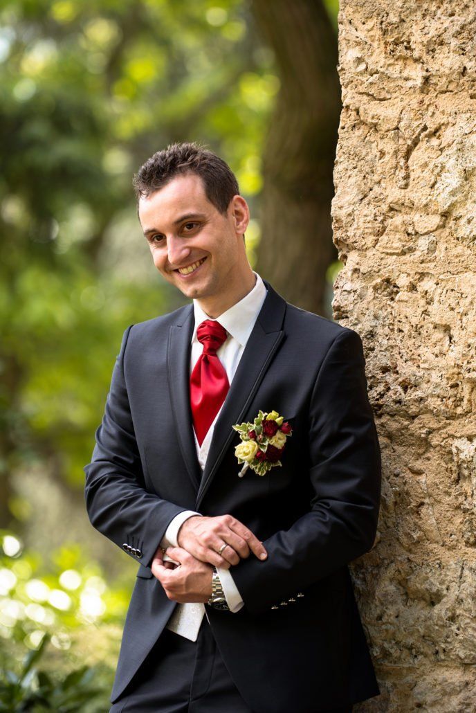 Ein Mann in Anzug und Krawatte lehnt an einer Wand.