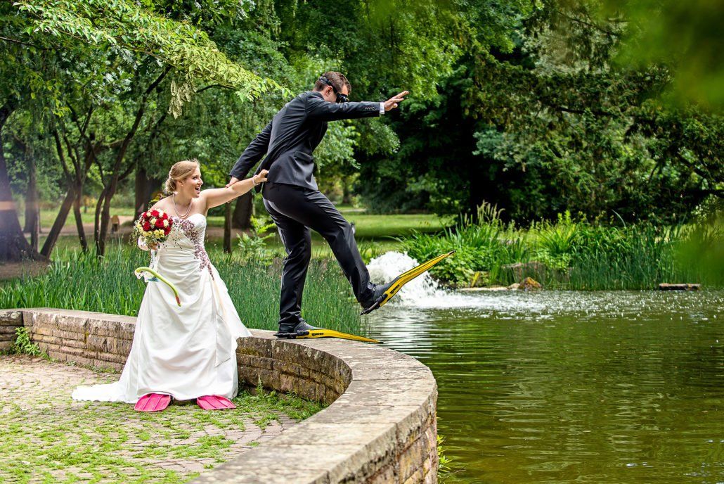 Eine Braut und ein Bräutigam posieren vor einem See für ein Foto.