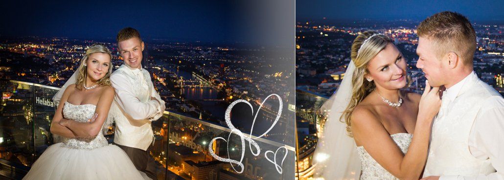 Eine Braut und ein Bräutigam posieren für ein Foto auf einem Balkon mit Blick auf eine Stadt bei Nacht.