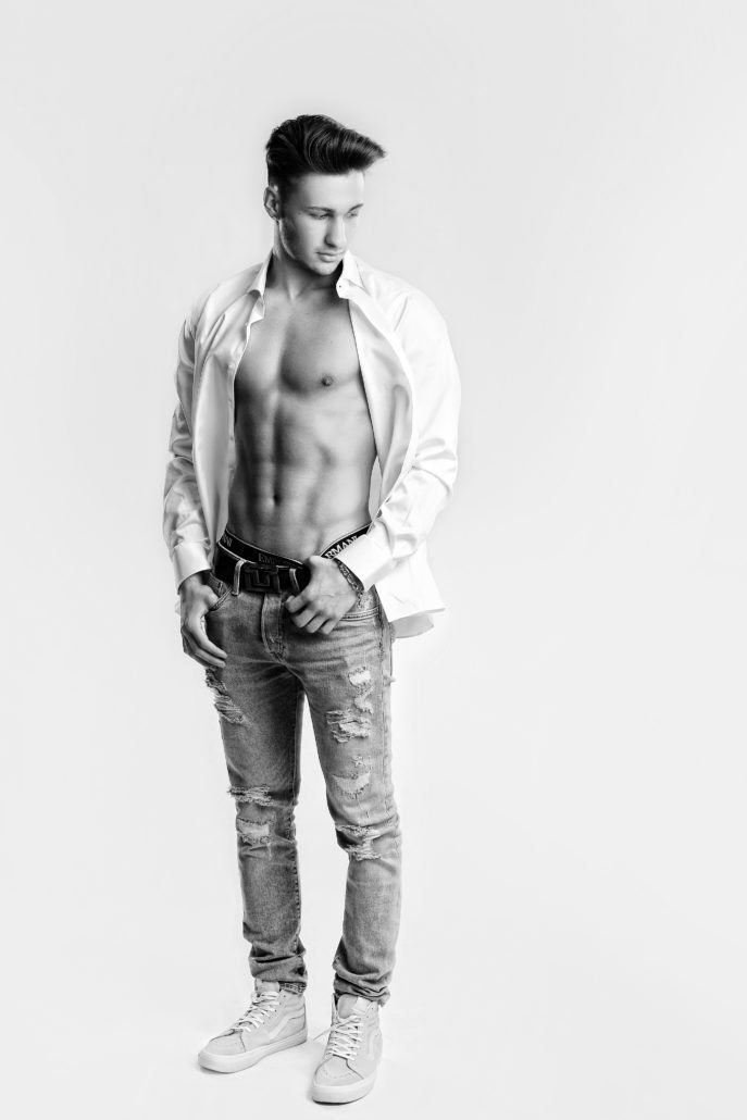 Auf einem Schwarzweißfoto steht ein Mann ohne Hemd.