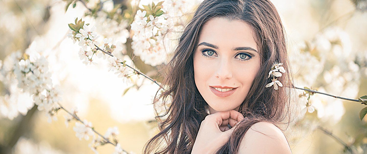 Eine Frau steht vor einem Baum mit weißen Blüten.