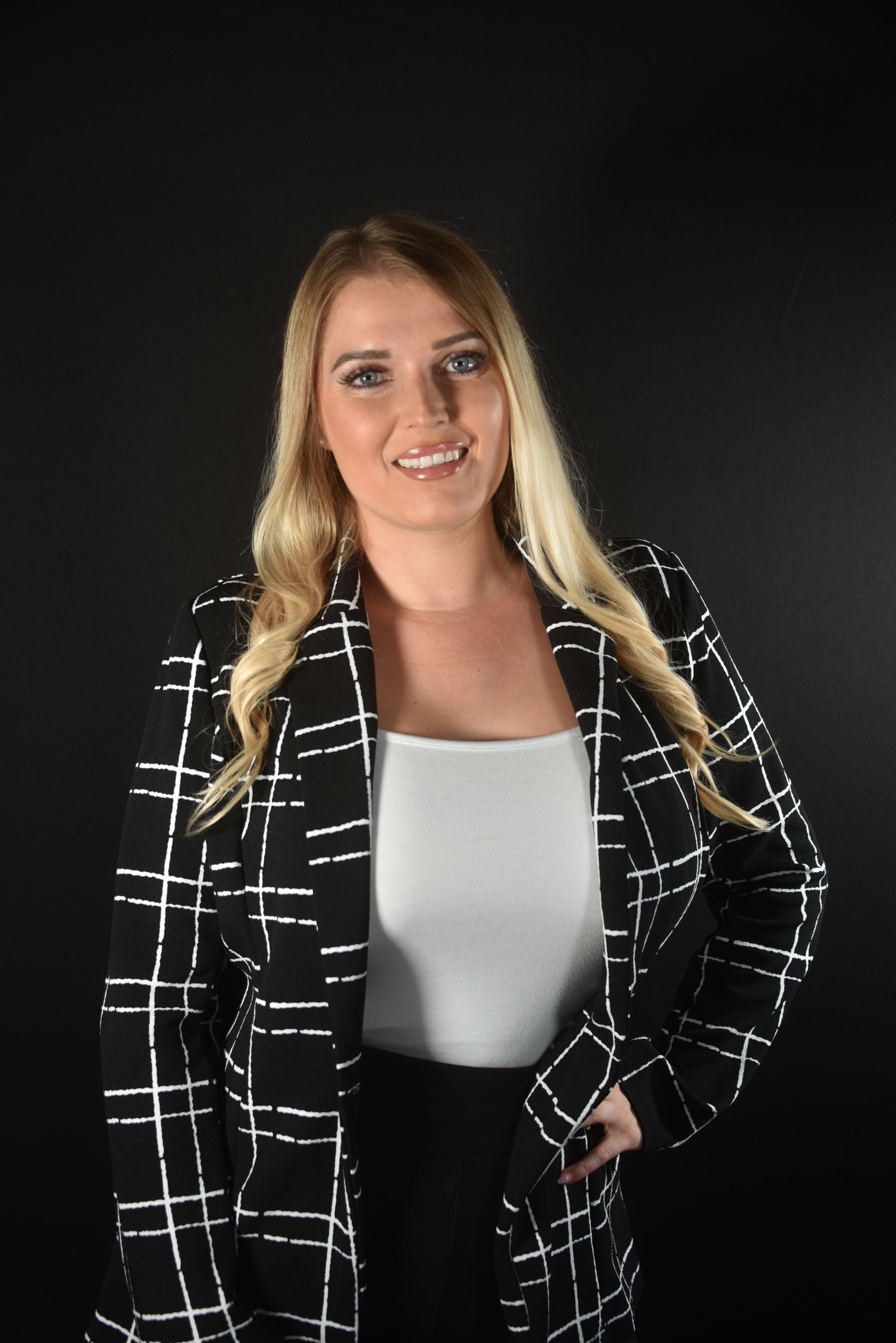 A woman is sitting at a desk with a laptop and a vase of flowers.