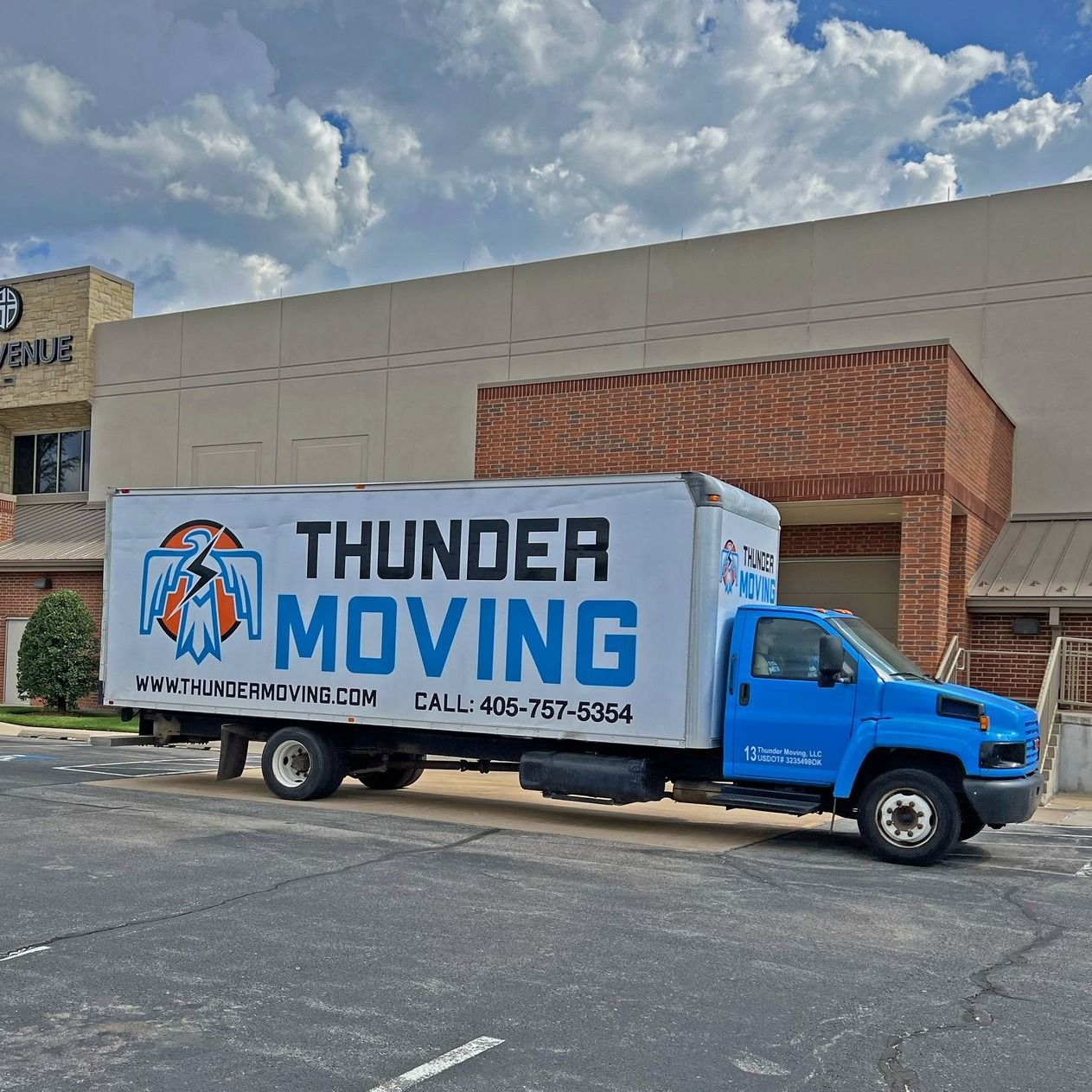 A Thunder Moving truck is parked in front of a building.