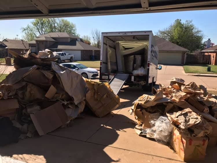 A moving truck is parked in a garage next to a pile of cardboard boxes.