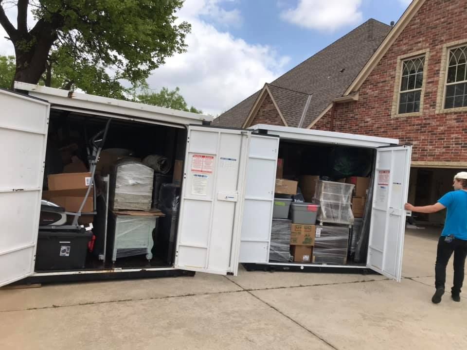 A man is standing in front of a storage container filled with boxes.