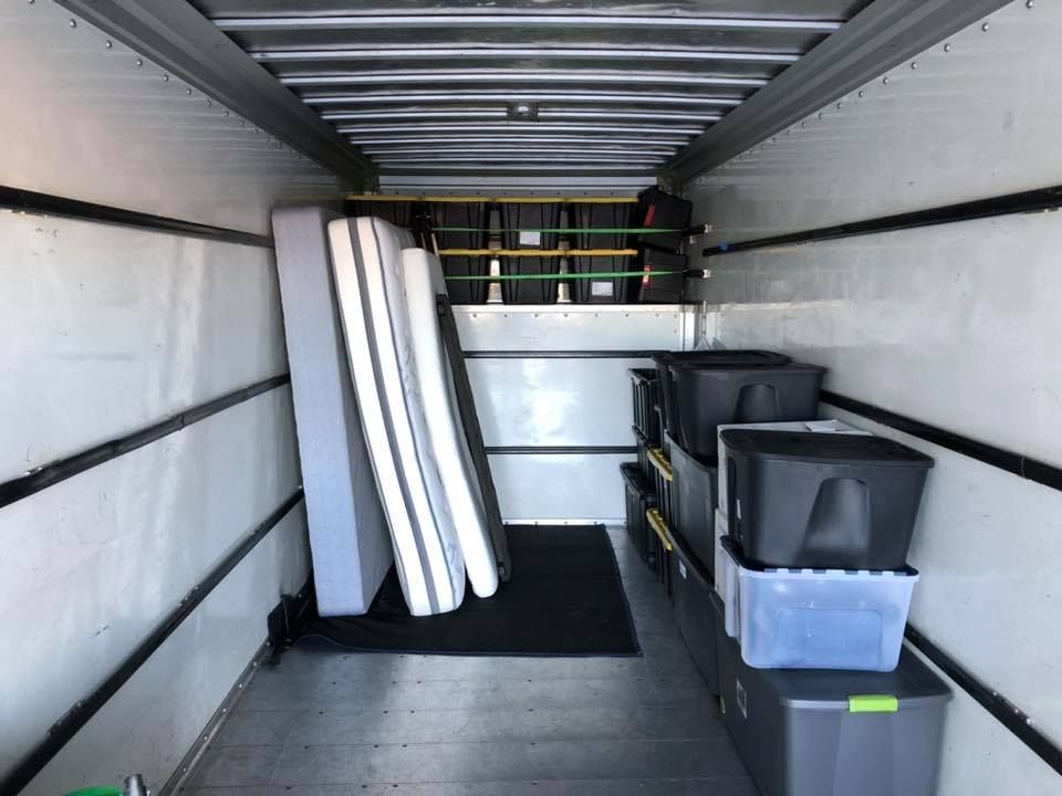 The inside of a moving truck filled with boxes and mattresses.