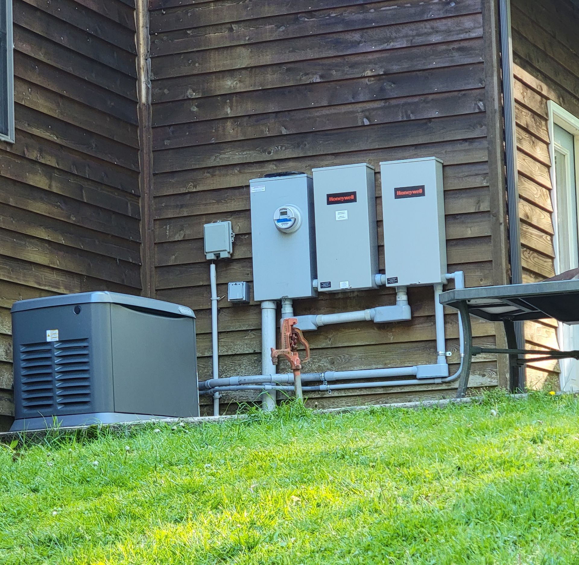 A generator is sitting on the side of a house.