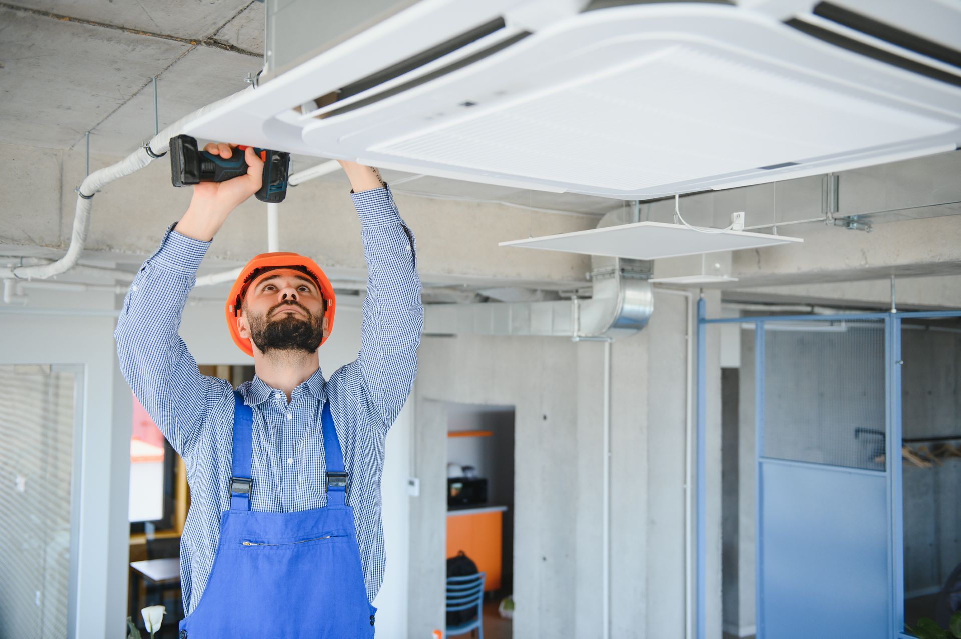 A man is installing a ceiling fan in an office.