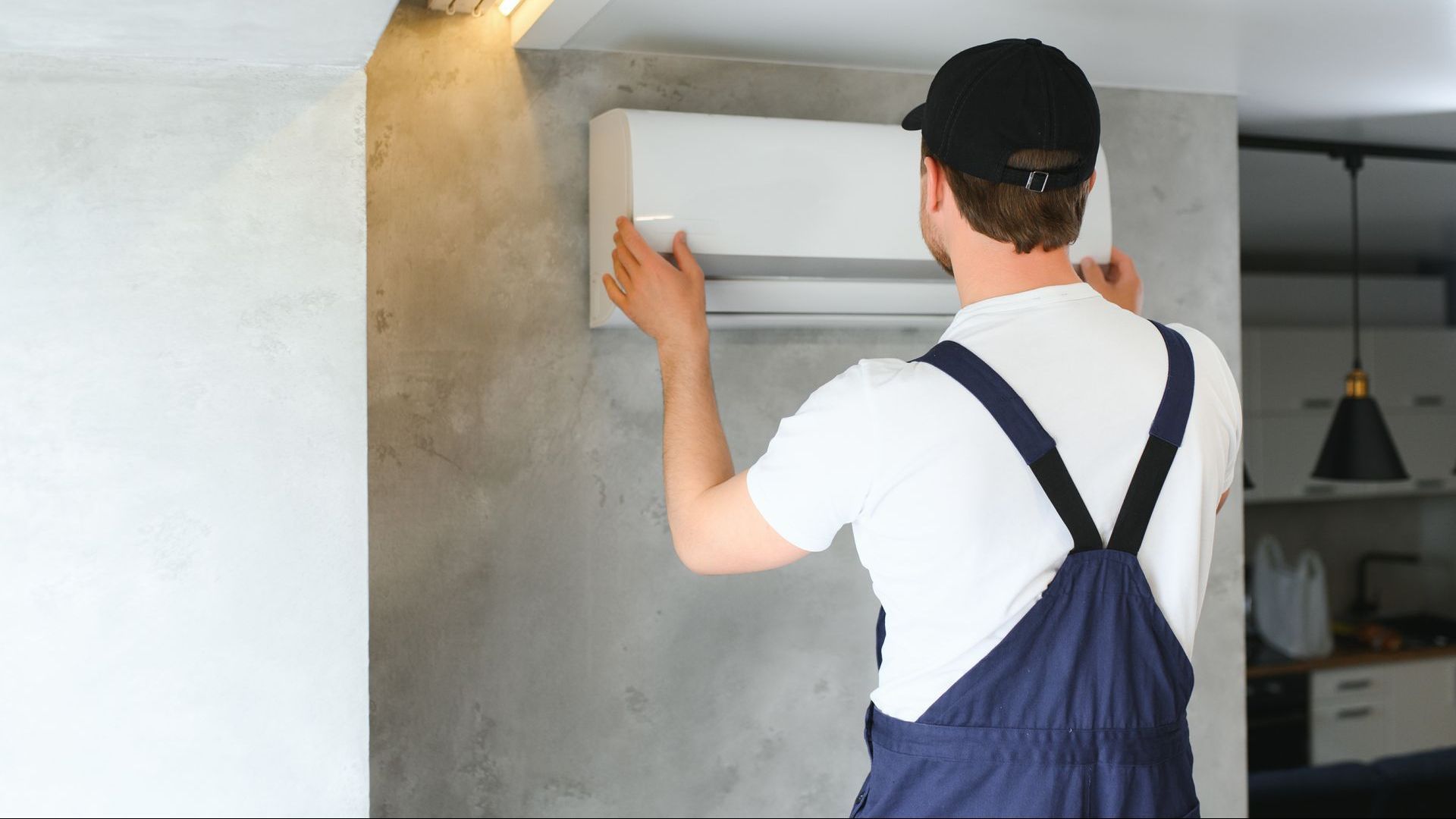 A man is installing an air conditioner on a wall.