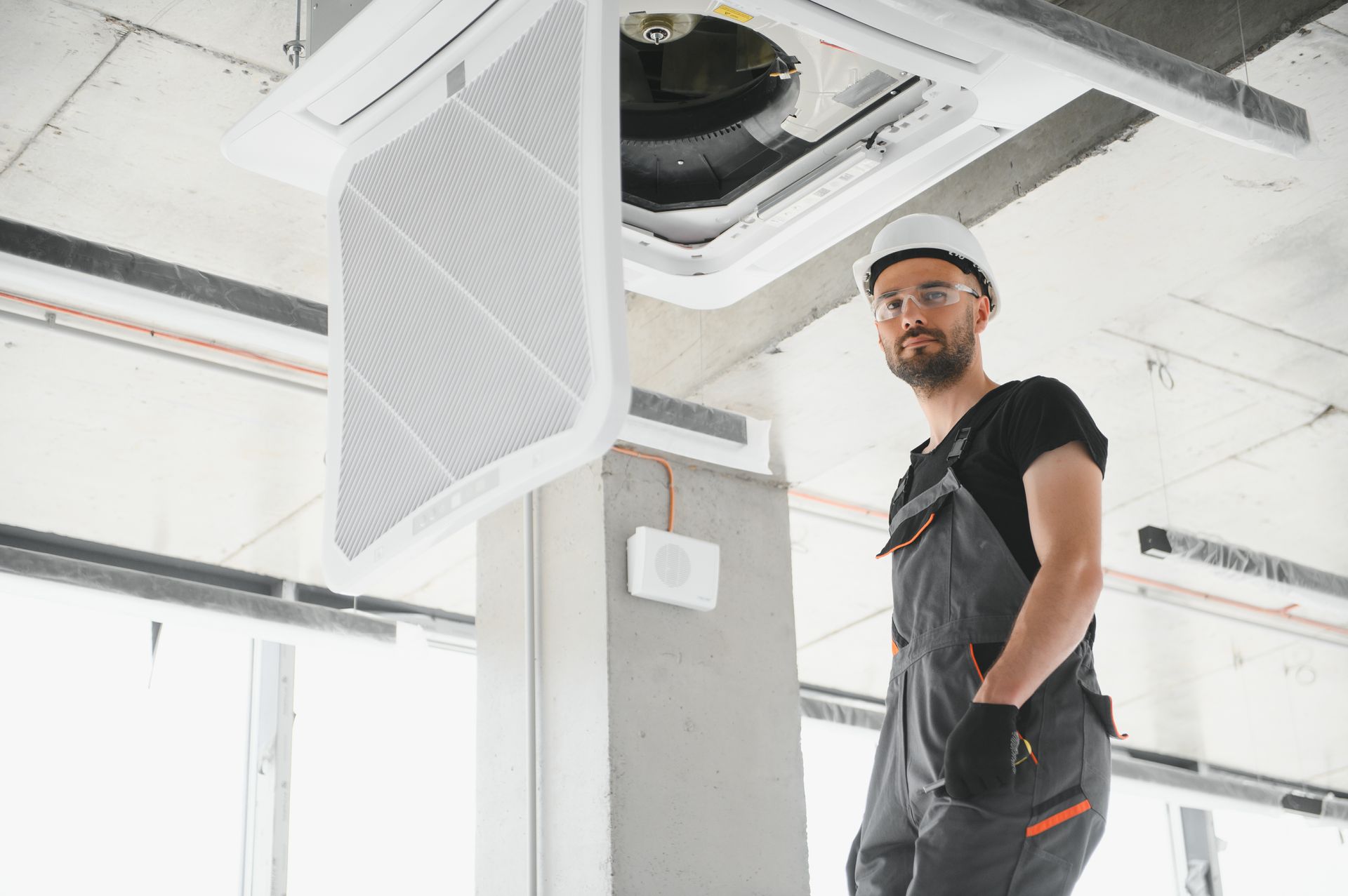 A man is working on a ceiling fan in a building.