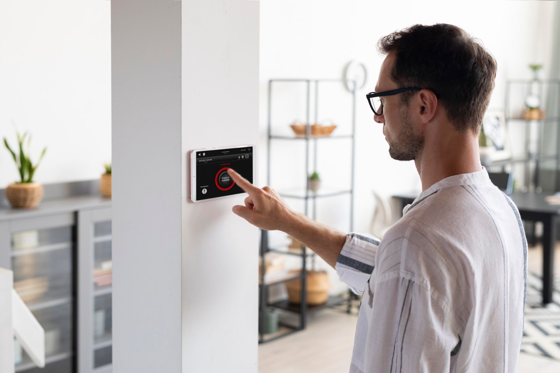 A man is using a smart thermostat in a living room.