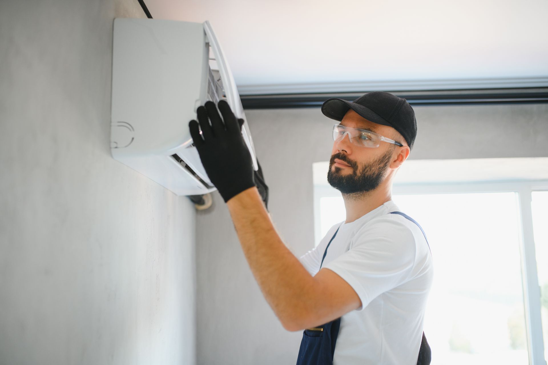 A man is installing an air conditioner on a wall.