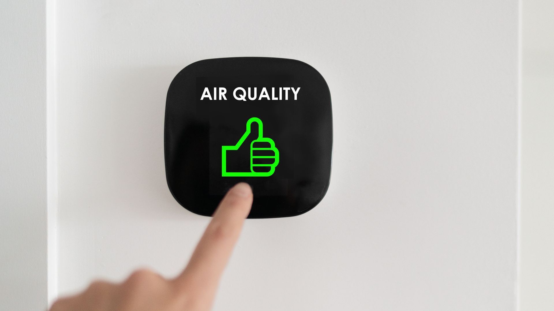 A person is pressing a button on a wall that says `` air quality ''.