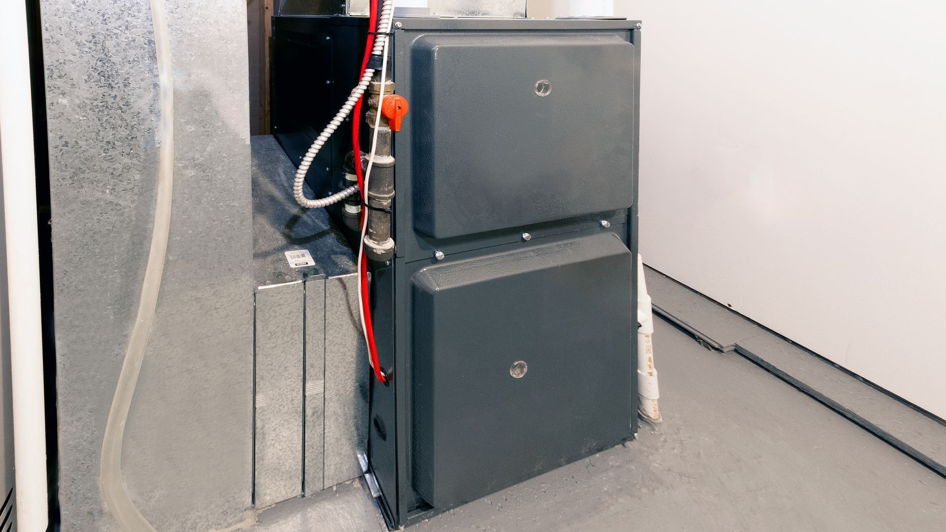 A large black furnace is sitting in a room next to a wall.